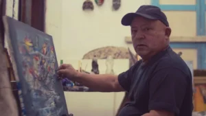 Nelson Domínguez pintando en su estudio con colores vibrantes.