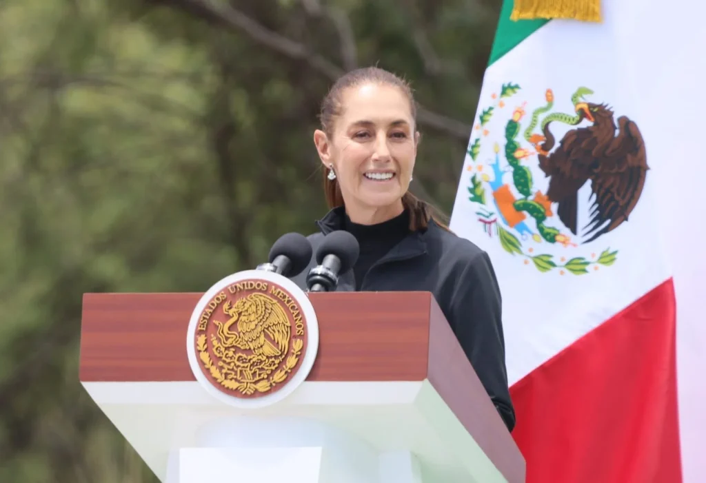 Claudia Sheinbaum en podio con bandera de México durante Jornada Nacional de Reforestación en Puebla