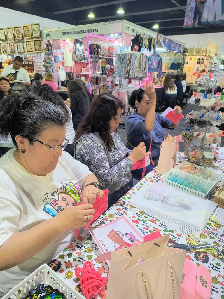 Participantes en taller de Expo Manualidades CDMX trabajando con hilo rosa en un ambiente creativo y comunitario