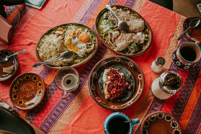Mesa mexicana con platillos tradicionales del recalentado del 15 de septiembre, acompañados de café y salsas.
